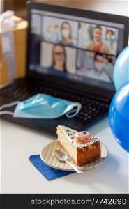 technology, pandemic and online party concept - piece of birthday cake on plate and laptop computer with video call on screen and mask at home. birthday cake and laptop with video call on screen