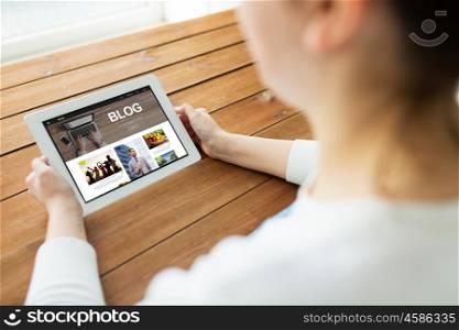 technology, people and blogging concept - close up of woman with blog page on tablet pc computer screen on wooden table