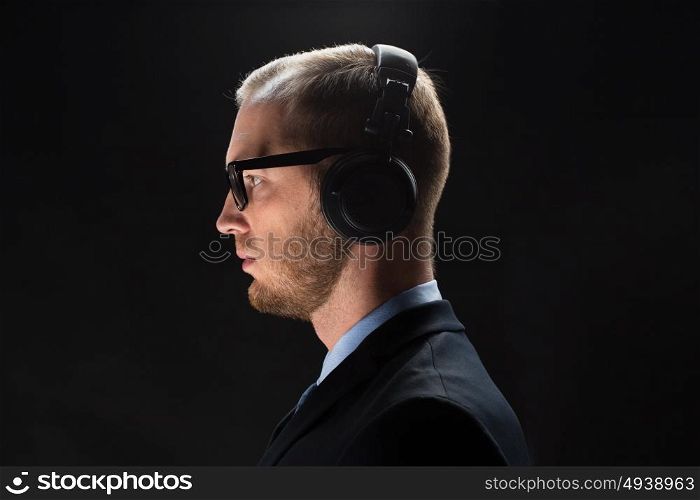 technology, people and business concept - businessman in headphones over black background. businessman in headphones