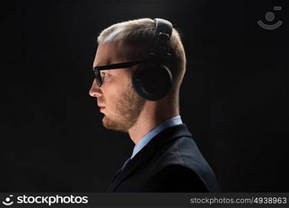 technology, people and business concept - businessman in headphones over black background. businessman in headphones