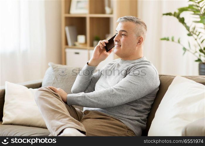 technology, people and communication concept - happy man calling on smartphone at home. happy man calling on smartphone at home. happy man calling on smartphone at home