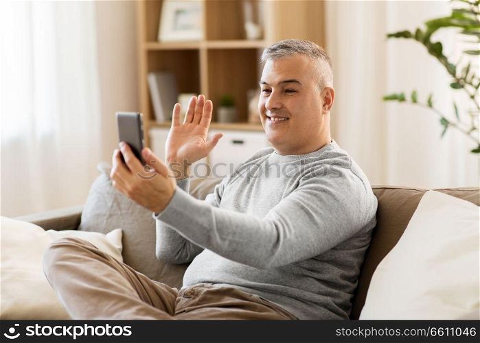 technology, people and communication concept - happy man having video chat on smartphone at home. man having video chat on smartphone at home