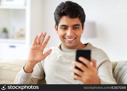 technology, people and communication concept - happy man with smartphone having video call at home. happy man having video call on smartphone at home