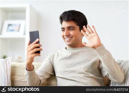 technology, people and communication concept - happy man with smartphone having video call at home. happy man having video call on smartphone at home