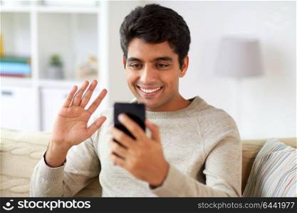 technology, people and communication concept - happy man with smartphone having video call at home. happy man having video call on smartphone at home