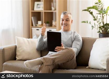 technology, people and communication concept - happy man with tablet pc computer having video chat at home and showing thumbs up. man having video chat on tablet pc at home. man having video chat on tablet pc at home
