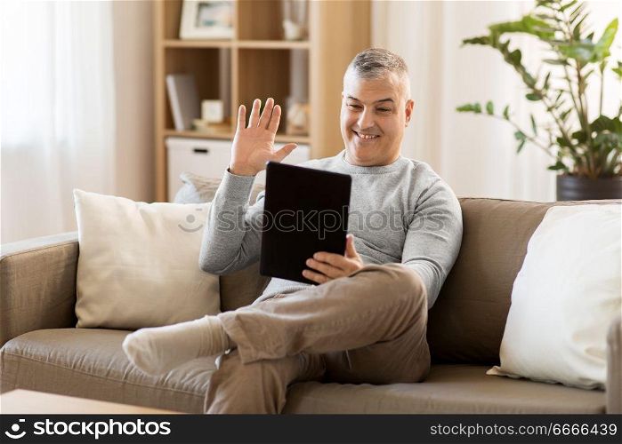technology, people and communication concept - happy man with tablet pc computer having video chat at home. man having video chat on tablet pc at home. man having video chat on tablet pc at home