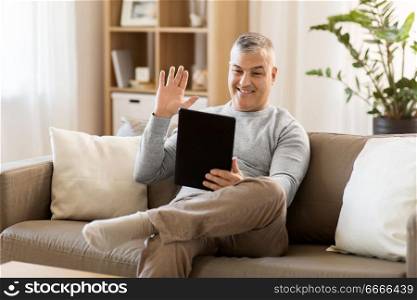 technology, people and communication concept - happy man with tablet pc computer having video chat at home. man having video chat on tablet pc at home. man having video chat on tablet pc at home