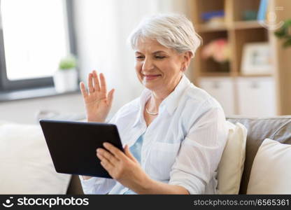 technology, people and communication concept - happy senior woman with tablet pc computer having video chat at home. senior woman having video chat on tablet pc