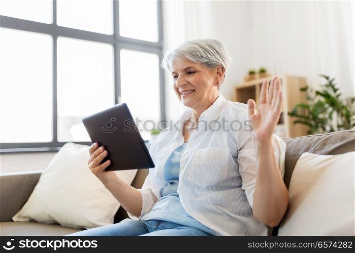 technology, people and communication concept - happy senior woman with tablet pc computer having video chat at home. senior woman having video chat on tablet pc