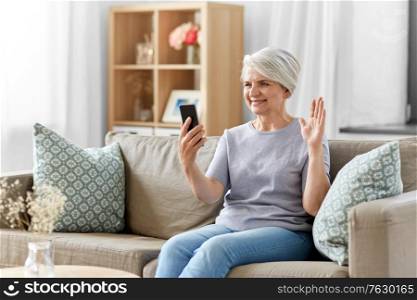 technology, people and communication concept - happy smiling senior woman with smartphone having video call at home. senior woman having video call on smartphone
