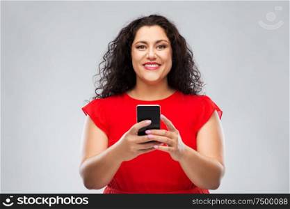 technology, people and communication concept - happy woman in red dress using smartphone over grey background. happy woman in red dress using smartphone