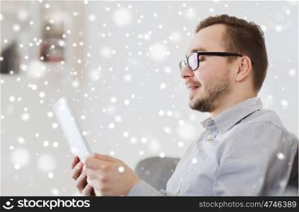 technology, people and distance learning concept - happy man working with tablet pc computer at home over snow