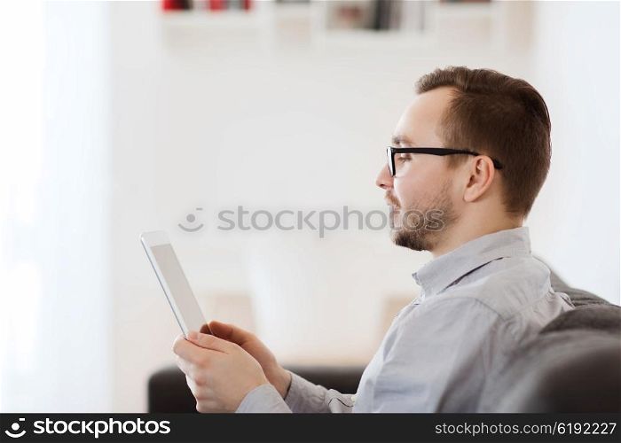 technology, people and distance learning concept - happy man working with tablet pc computer at home