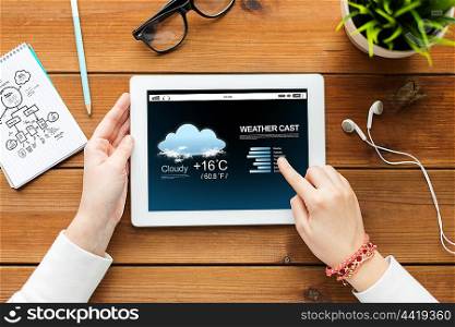 technology, people and forecast concept - close up of woman with weather cast on tablet pc computer screen on wooden table