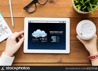 technology, people and forecast concept - close up of woman with weather cast on tablet pc computer screen and coffee on wooden table