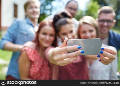 technology, people and friendship concept - happy friends with smartphone taking selfie at summer party. friends with smartphone taking selfie at summer