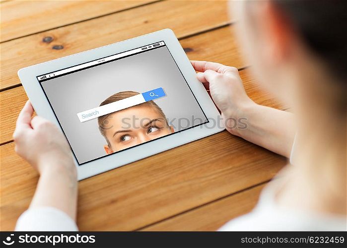technology, people and internet concept - close up of woman with web browser search bar on tablet pc computer screen on wooden table