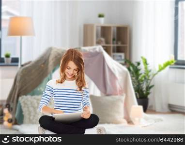 technology, people and internet concept - little student girl with tablet pc at home over kids room and tepee background. student girl with tablet pc at home