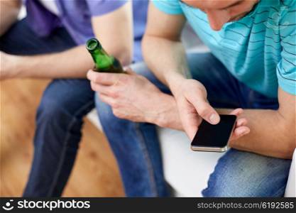 technology, people and leisure concept - close up of man with smartphone texting massage and drinking beer at home
