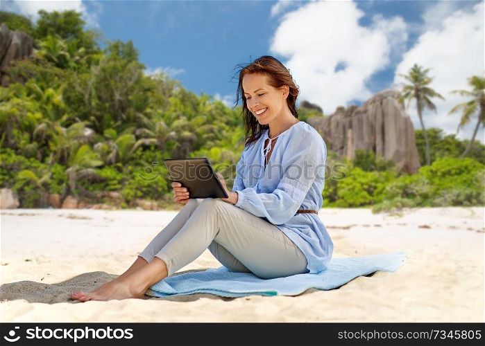 technology, people and leisure concept - happy smiling woman with tablet pc computer over tropical beach on seychelles island background. happy smiling woman with tablet pc on summer beach