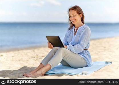 technology, people and leisure concept - happy smiling woman with tablet pc computer on summer beach. happy smiling woman with tablet pc on summer beach