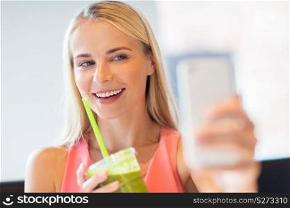 technology, people and leisure concept - happy woman with smartphone and smoothie drink or vegetarian shake taking selfie at restaurant. woman with smartphone taking selfie at restaurant