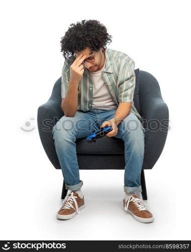 technology, people and leisure concept - sad man in glasses with gamepad sitting in chair loosing video game over white background. sad man with gamepad loosing video game