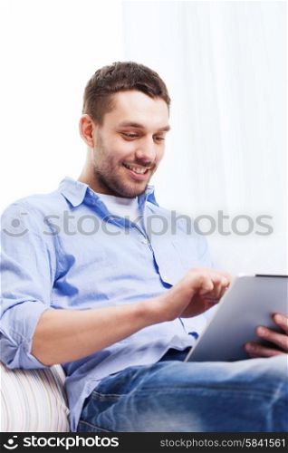 technology, people and leisure concept - smiling young man with tablet pc computer at home