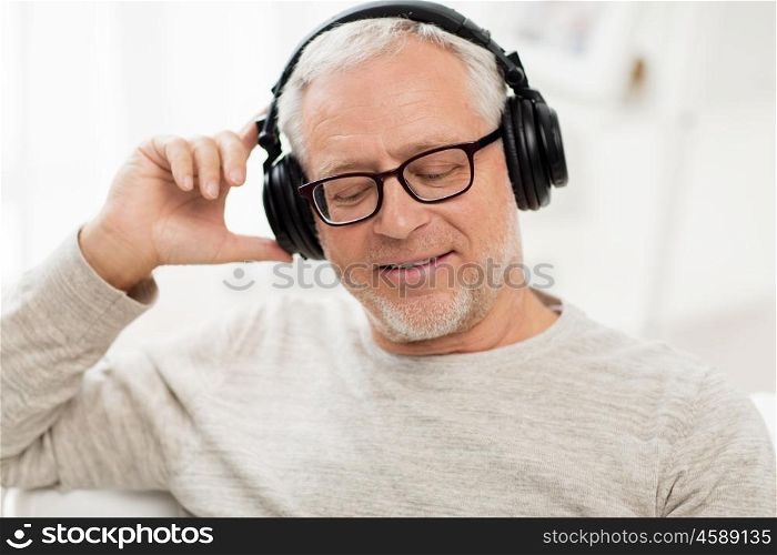 technology, people and lifestyle concept - close up of happy senior man in headphones listening to music at home. happy man in headphones listening to music at home