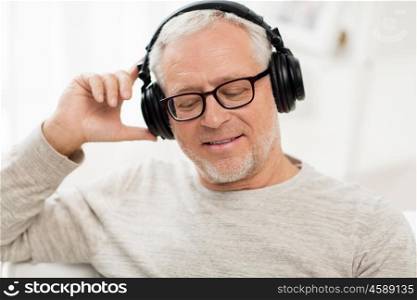 technology, people and lifestyle concept - close up of happy senior man in headphones listening to music at home. happy man in headphones listening to music at home