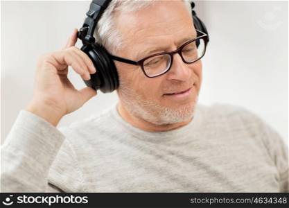 technology, people and lifestyle concept - close up of happy senior man in headphones listening to music at home