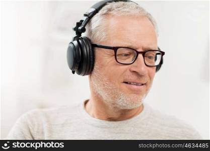 technology, people and lifestyle concept - close up of happy senior man in headphones listening to music at home