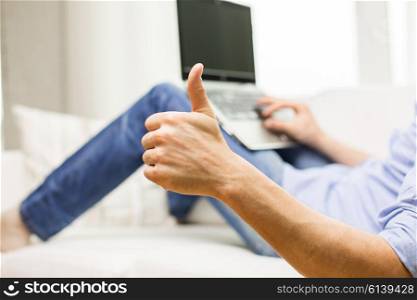 technology, people and lifestyle concept - close up of male hands typing on laptop computer and showng thumbs up at home