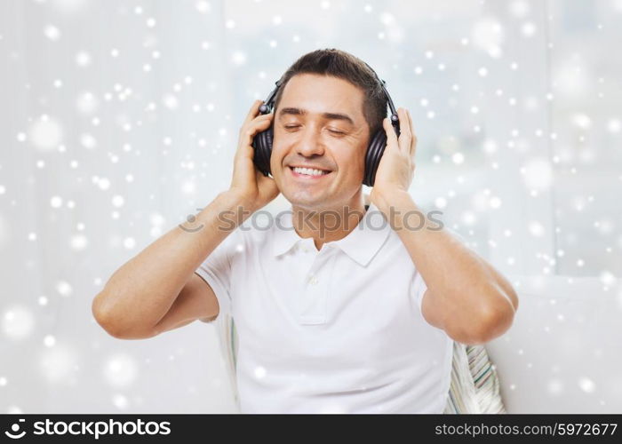 technology, people and lifestyle concept - happy man in headphones listening to music at home over snow effect