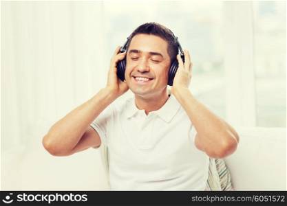technology, people and lifestyle concept - happy man in headphones listening to music at home