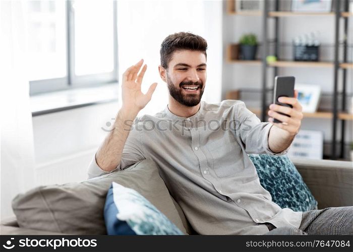 technology, people and lifestyle concept - happy man with smartphone having video call at home. man with smartphone having video call at home