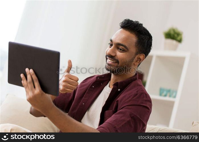 technology, people and lifestyle concept - happy man with tablet pc computer having video chat at home and showing thumbs up. happy man with tablet pc having video chat at home