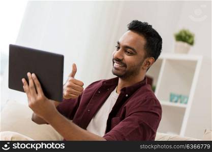 technology, people and lifestyle concept - happy man with tablet pc computer having video chat at home and showing thumbs up. happy man with tablet pc having video chat at home