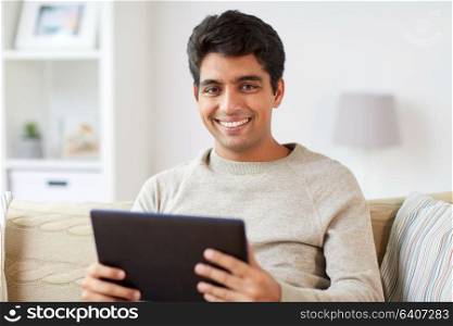 technology, people and lifestyle concept - happy man with tablet pc computer at home. smiling man with tablet pc at home
