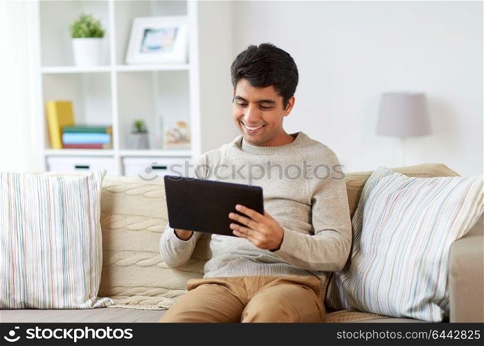 technology, people and lifestyle concept - happy man with tablet pc computer at home. smiling man with tablet pc at home