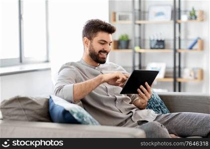 technology, people and lifestyle concept - happy man with tablet pc computer at home. smiling man with tablet computer at home