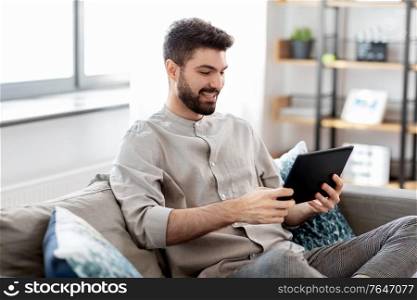 technology, people and lifestyle concept - happy man with tablet pc computer at home. smiling man with tablet computer at home