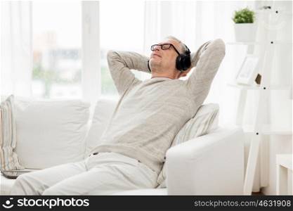 technology, people and lifestyle concept - happy senior man in headphones listening to music at home