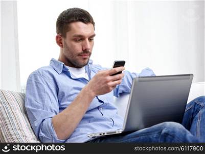 technology, people and lifestyle concept - man with smartphon and laptop computer working at home