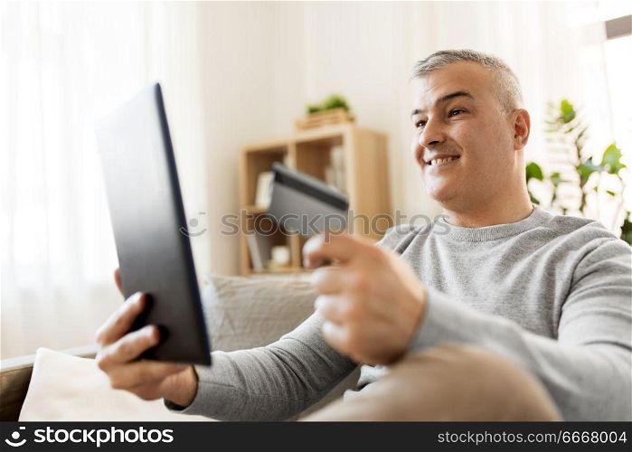 technology, people and lifestyle concept - man with tablet pc computer and credit card shopping online or using internet bank at home. man with tablet pc and credit card shopping online. man with tablet pc and credit card shopping online