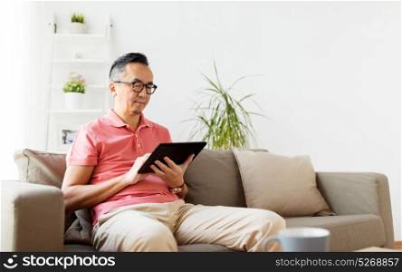 technology, people and lifestyle concept - man with tablet pc sitting on sofa at home. man with tablet pc sitting on sofa at home