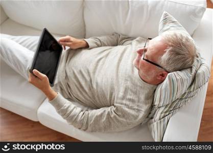 technology, people and lifestyle concept - senior man with black blank tablet pc computer screen lying on sofa at home. senior man with tablet pc lying on sofa at home