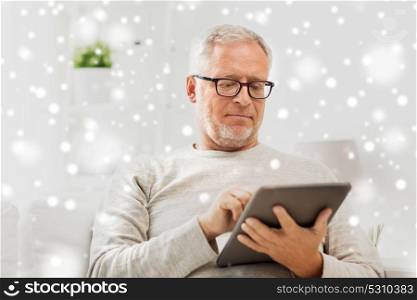 technology, people and lifestyle concept - senior man with tablet pc computer at home over snow. senior man with tablet pc at home