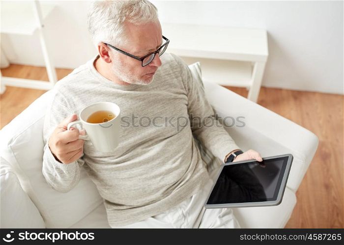 technology, people and lifestyle concept - senior man with tablet pc computer drinking tea at home